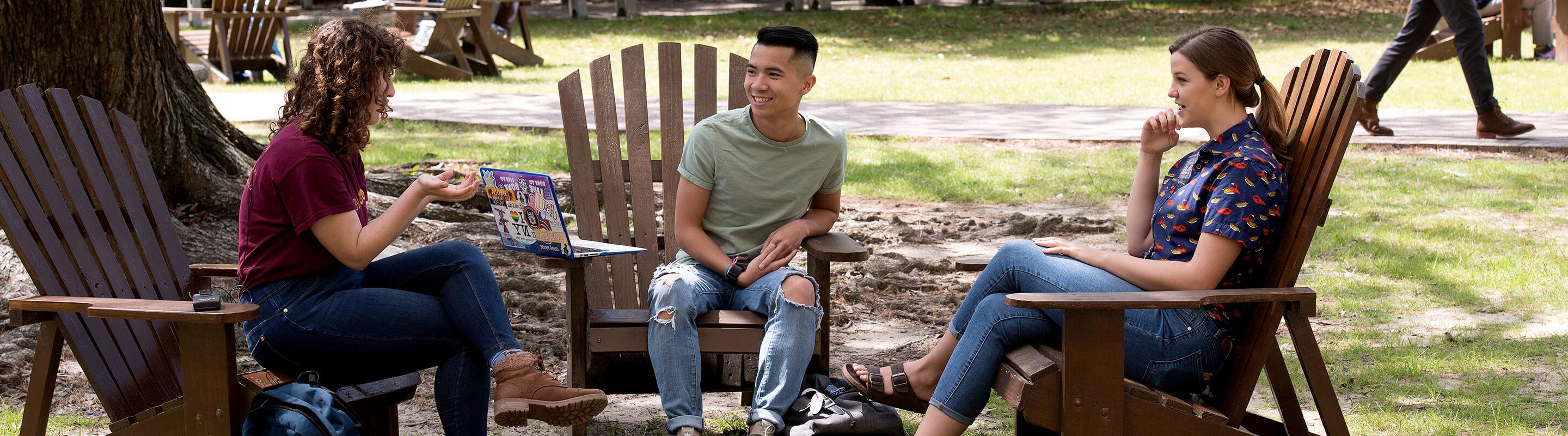 Three students having discussion on lawn